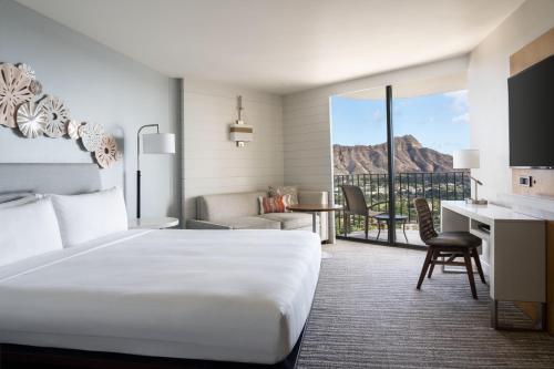 a hotel room with a bed and a desk with a view at Waikiki Beach Marriott Resort & Spa in Honolulu