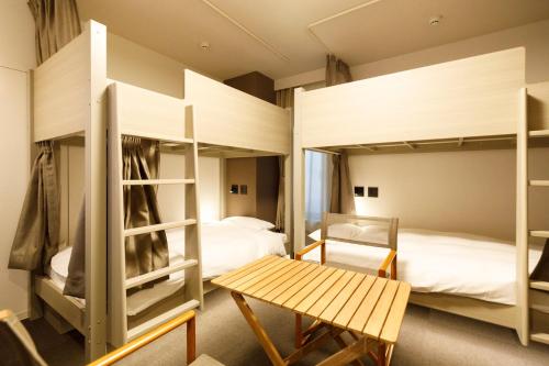 a room with two bunk beds and a table at HOTEL Third Place Hakata in Fukuoka