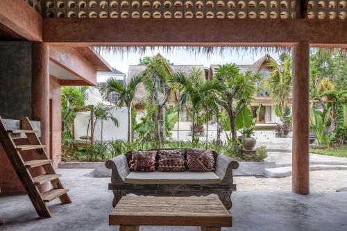 a patio with a couch and a table and palm trees at Lulu's Villas in Uluwatu