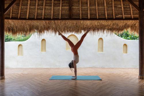 Uma mulher numa pose de ioga num tapete de ioga. em Lulu's Villas em Uluwatu