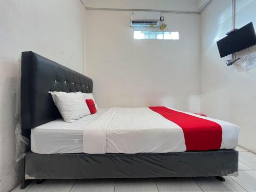 a bedroom with a bed with a red and white blanket at RedDoorz Syariah at Falisha UMY in Ngabean