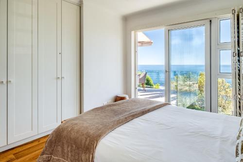 a bedroom with a bed and a large window at Beach Steps in Cape Town