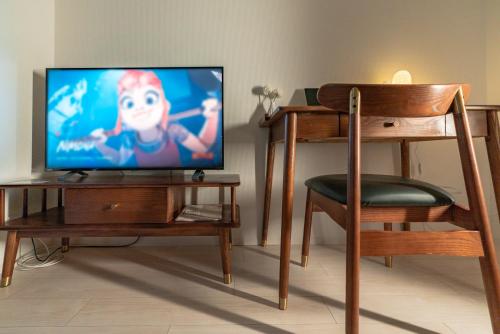 a flat screen tv sitting on a wooden stand with a chair at 谷町君ホテル　難波80 in Osaka