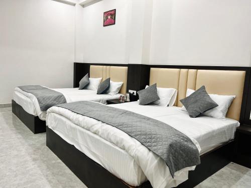 Duas camas num quarto com paredes brancas em Dhaneshwari Homestay em Varanasi