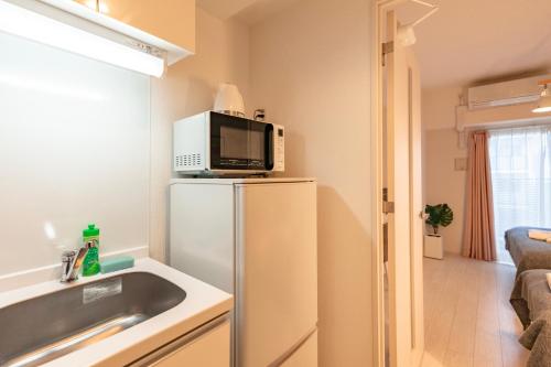 a small kitchen with a microwave on top of a refrigerator at 谷町君ホテル　難波80 in Osaka