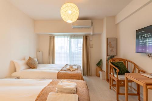 um quarto com 2 camas, uma mesa e uma televisão em 谷町君ホテル　難波80 em Osaka