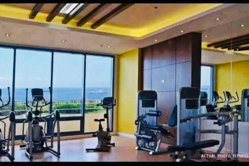 a gym with cardio equipment and large windows at Grand Riviera Suites2 @ US embassy/freepool/Wi-Fi in Manila