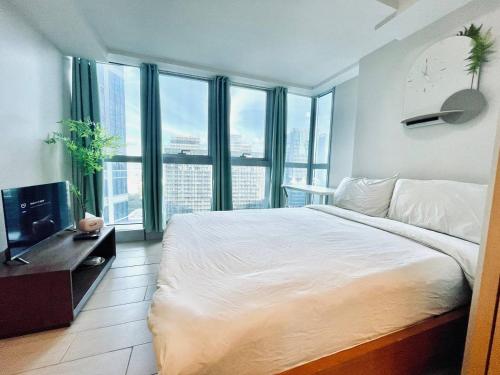a bedroom with a large bed and large windows at Thompson Suites - 2 beds, Uptown Parksuites Tower 1 25F in Manila
