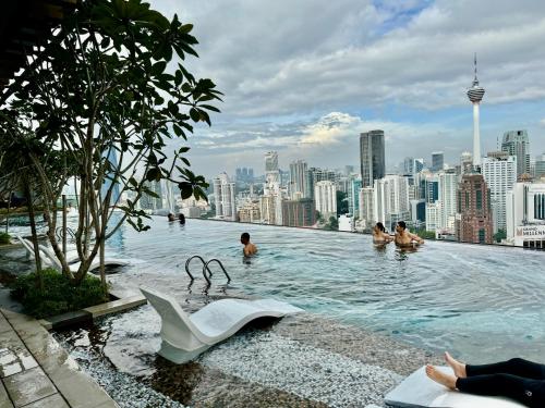 a swimming pool on the roof of a building with people in it at Axon Residence By Luxury Suites in Kuala Lumpur