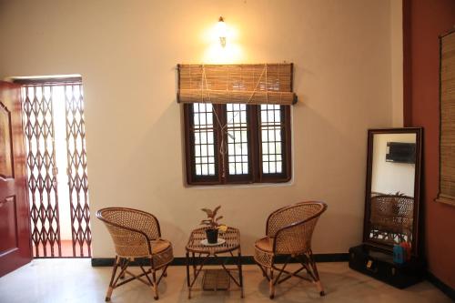 une chambre avec des chaises, une table et un miroir dans l'établissement Gs Gardenia Homestay, à Madurai