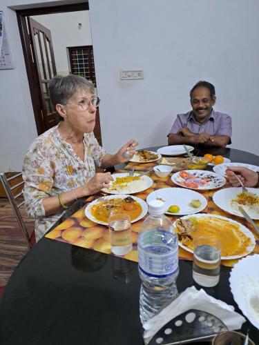 a group of people sitting at a table eating food at Marari Bethsaida Homestay in Shertallai