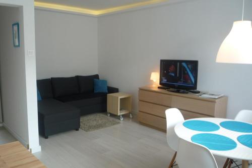 Mieszkanie Przy Plaży في غدانسك: غرفة معيشة مع أريكة وطاولة مع تلفزيون