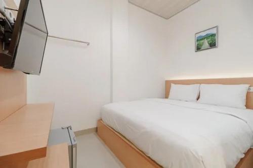 - une chambre blanche avec un lit et une télévision dans l'établissement The Paragon Hotel Cilacap Redpartner, à Cilacap