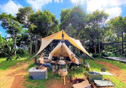 dos hombres sentados en una tienda en el césped en Katsuyama Basecamp - Camp - Vacation STAY 42349v, en Yamanuha