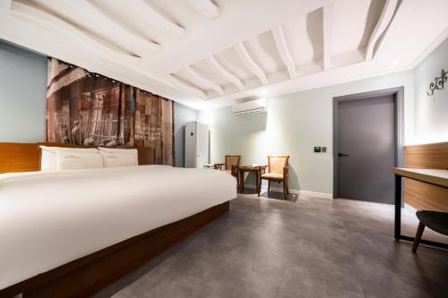 - une chambre avec un grand lit et un bureau dans l'établissement Hotel New Evergreen, à Mokpo