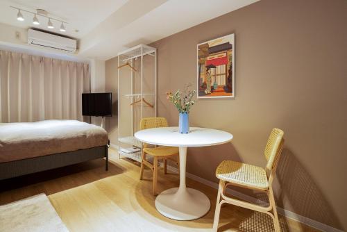 東京にあるSection L Residence Ginzaのベッド、テーブル、椅子が備わる客室です。
