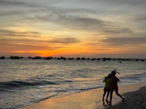 two people walking on the beach at sunset at Barland Villa in Ke Ga