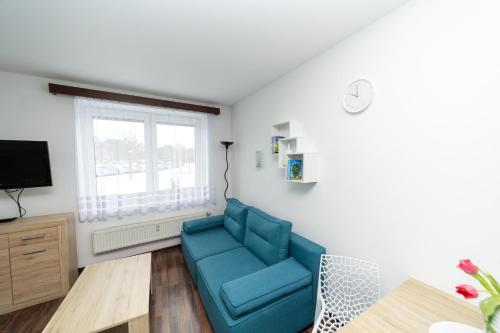 a living room with a blue couch and a tv at Penzion Bludička in Litomyšl