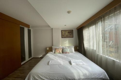 a bedroom with a large white bed with a window at Landmark Patong Hotel in Patong Beach