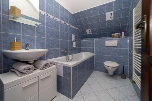 a blue tiled bathroom with a sink and a toilet at Penzion Bludička in Litomyšl