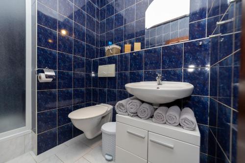 a blue tiled bathroom with a sink and a toilet at Penzion Bludička in Litomyšl