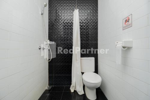 a bathroom with a toilet and a shower curtain at Palm Eight Mitra RedDoorz in Jakarta