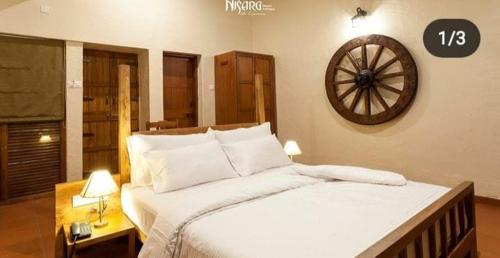 1 dormitorio con 1 cama grande y reloj en la pared en Nisarg Resort, en Kolhapur