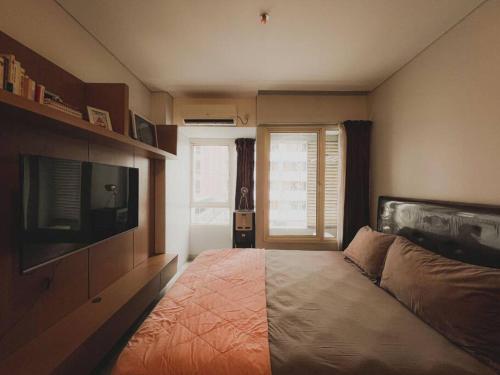 1 dormitorio con 1 cama y TV en Vintage Oasis Retro Studio at Nifarro Apartment, en Yakarta