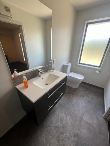 a bathroom with a sink and a toilet and a mirror at Southern Comfort in Kurow