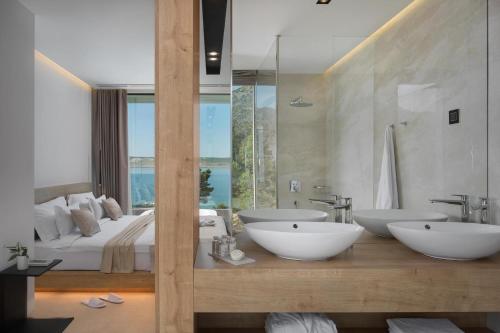 een badkamer met 2 wastafels en een bed bij 5-Star Villa Calma I with Heated Pool, Jacuzzi, Sea and Palm Tree Garden in Starigrad-Paklenica