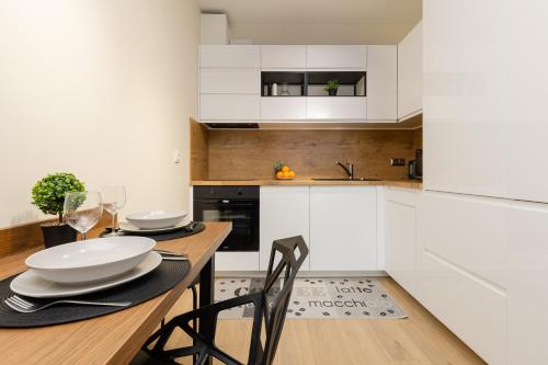 cocina con mesa de madera y armarios blancos en Cozy Studio Apartment in Ursus District by Renters, en Varsovia
