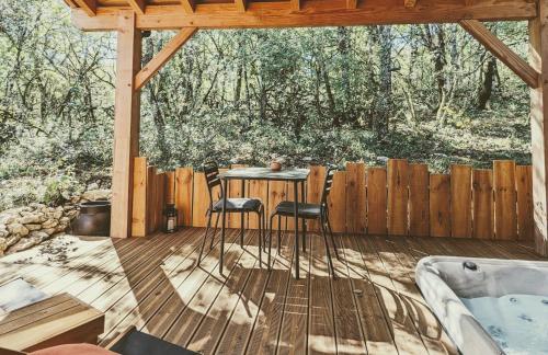 Aux Trois Chênes Lodge Spa في ميرْكو: سطح خشبي مع طاولة وكرسيين