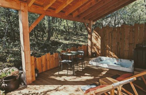 Aux Trois Chênes Lodge Spa في ميرْكو: سطح خشبي مع طاولة وحوض استحمام ساخن