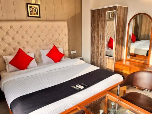 グルガオンにあるHotel Graciousのベッドルーム1室(赤い枕と鏡付きのベッド1台付)