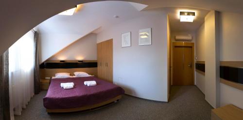 a bedroom with a purple bed with towels on it at Hotel KARO in Radom