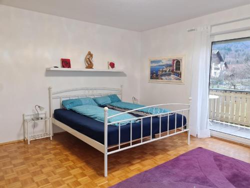 Schlafzimmer mit einem Bett mit blauer Bettwäsche und einem Fenster in der Unterkunft Ferienhaus Falkenstein in Frauenau