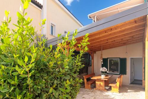 a patio with a wooden pergola and a wooden table at Apartments TM in Krk