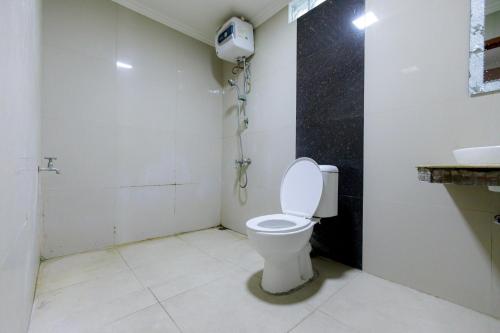 a bathroom with a toilet and a phone on the wall at RedDoorz Syariah at Delta Sari Aloha Waru in Sidoarjo