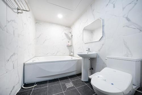 a white bathroom with a toilet and a sink at Hotel New Evergreen in Mokpo