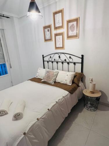 1 dormitorio con 1 cama grande con sábanas y almohadas blancas en Apartamento Don Pedro, en Valencia de Alcántara