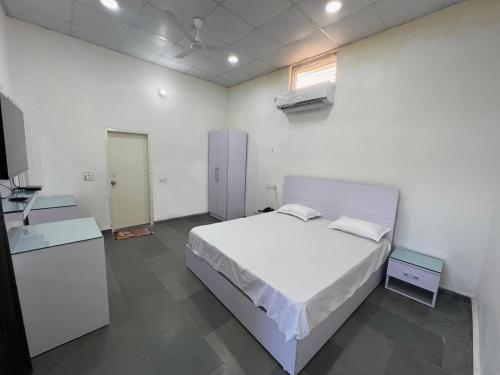 1 dormitorio con 1 cama blanca y TV en Zoravar Farms, en Sohna