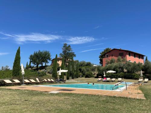 a swimming pool with chairs and a building in the background at Agriturismo Corte in Poggio in Stabbia