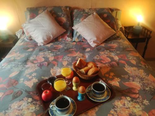 a breakfast tray with eggs and bread on a bed at Chez ROMU in Rieutort