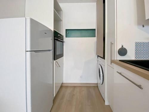uma cozinha branca com um frigorífico e um lavatório em Le Saint Pierre - T2 refait em Saint-Pierre-de-Chandieu
