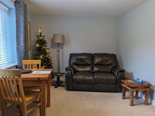 uma sala de estar com um sofá de couro e uma árvore de Natal em Gables Farm, Self contained flat by Middlewood Way em Poynton