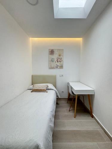 een kleine slaapkamer met een bed en een bureau bij ATICO VISTAS MAR PLAYA LAS CANTERAS in Las Palmas de Gran Canaria