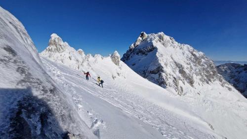 two people skiing down a snow covered mountain at Koča Kopriva in Križe