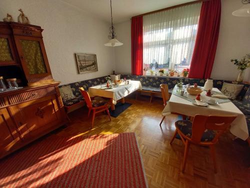 ein Esszimmer mit 2 Tischen und roten Vorhängen in der Unterkunft Pension Bitter in Reinhardshausen
