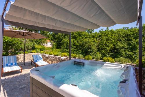 a hot tub with an umbrella and two chairs at Vila Marak in Risika