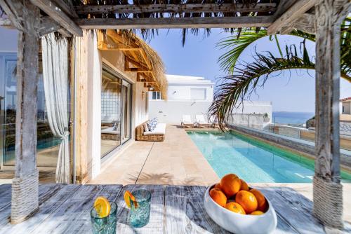 a bowl of oranges on a table next to a swimming pool at MEDANO4YOU Ixchel Beach House in El Médano